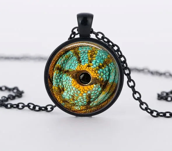 Collier avec un pendentif rond orné d’un motif vert et marron sur fond blanc

