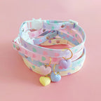 Collier à pois pastel avec pendentifs en forme de cœur sur fond rose


