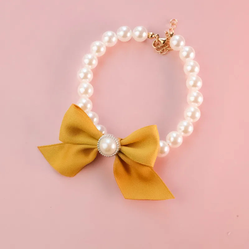 Bracelet en perles avec un nœud jaune et un centre de perle sur fond rose

