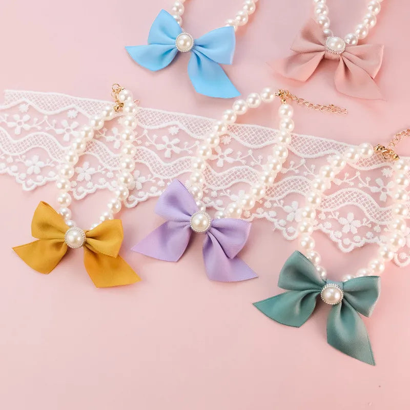Colliers avec des pendentifs colorés en forme de nœud sur fond en dentelle rose


