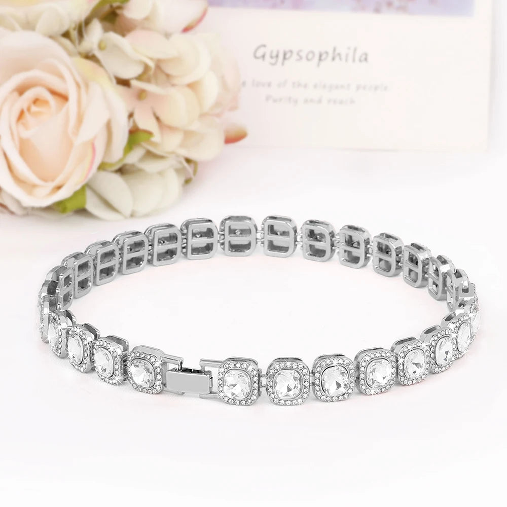 Bracelet en argent avec des pierres transparentes sur fond blanc et des fleurs
