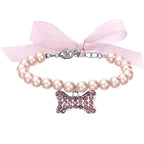 Bracelet en perles avec un nœud rose et un pendentif en forme de nœud sur fond blanc

