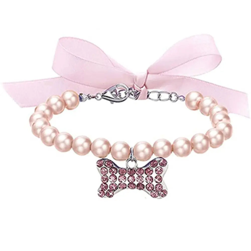 Bracelet en perles avec un nœud rose et un pendentif en forme de nœud sur fond blanc

