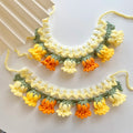 Collier au crochet avec des pompons floraux sur fond blanc

