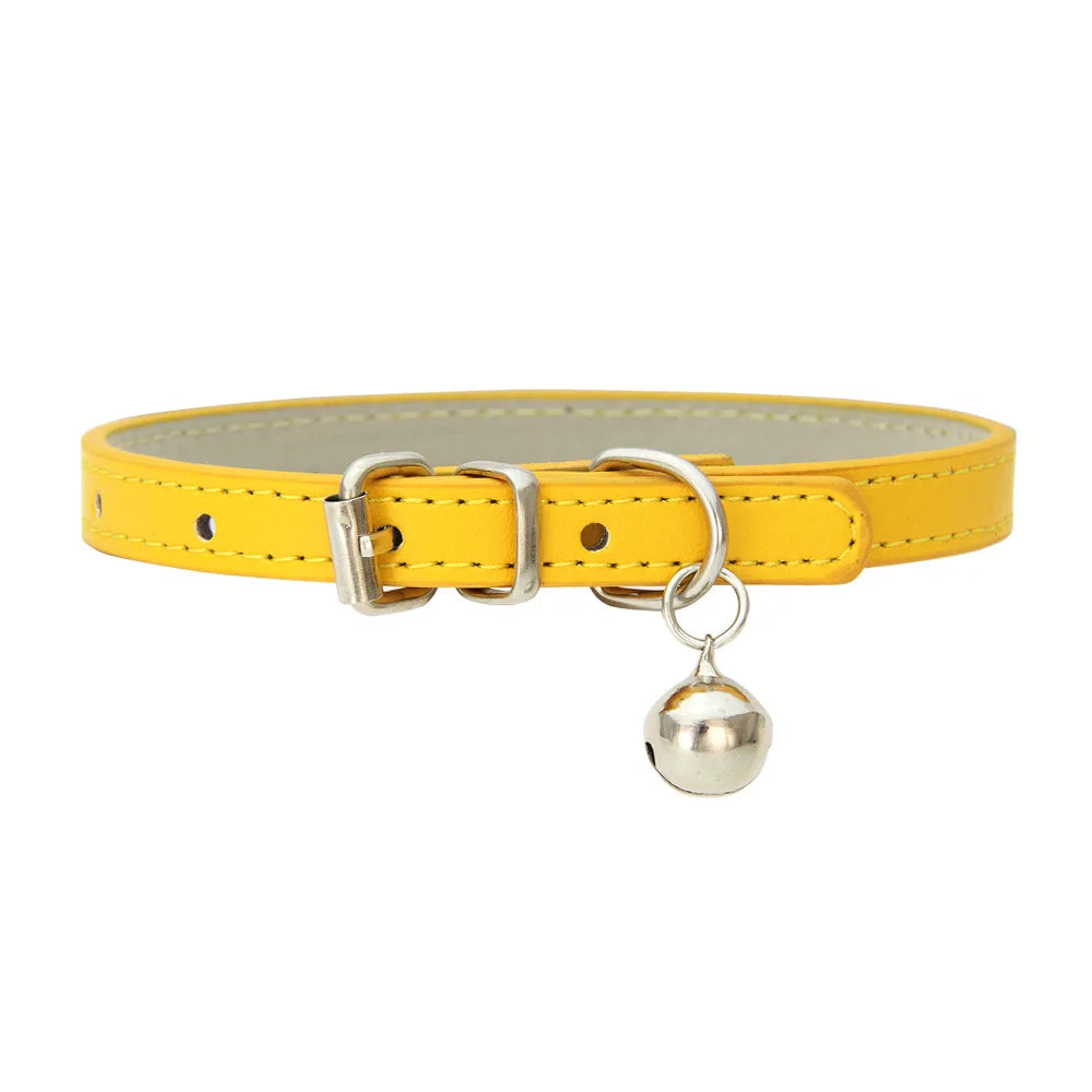 Collier de chat en cuir jaune avec une clochette argentée sur fond blanc

