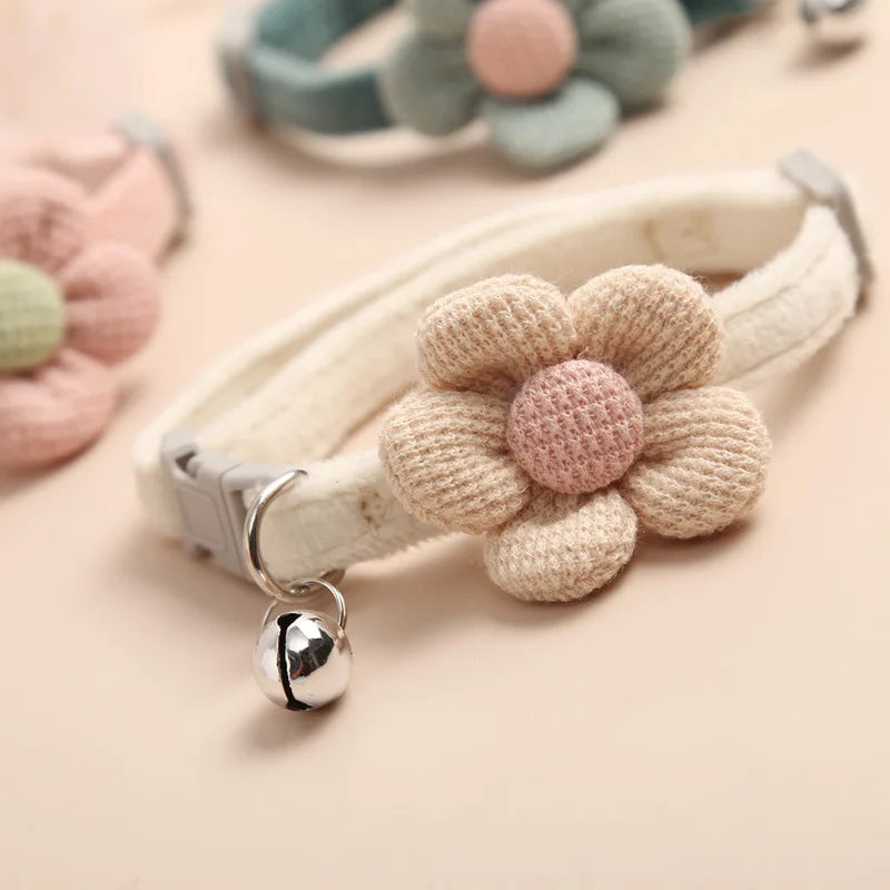 Collier pour animaux avec une fleur tricotée et une clochette sur un fond doux

