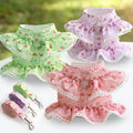Trois robes florales pour animaux vertes, roses et violettes avec des laisses assorties sur une surface blanche.

