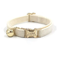 Collier pour chien avec clochette dorée et plaque nominative gravée sur fond blanc

