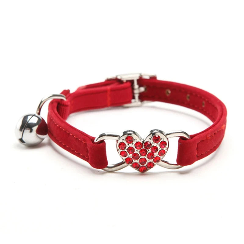Collier rouge pour chat avec une boucle métallique en forme de cœur et une clochette sur fond blanc

