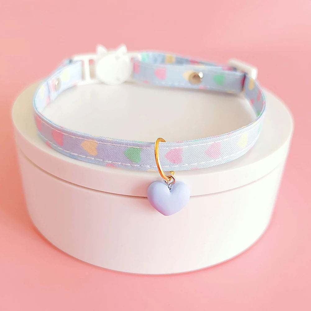 Collier pour chat avec un pendentif en forme de cœur sur fond rose

