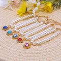 Collier de perles avec des breloques colorées en forme de cœur sur une surface texturée avec des fleurs en fond

