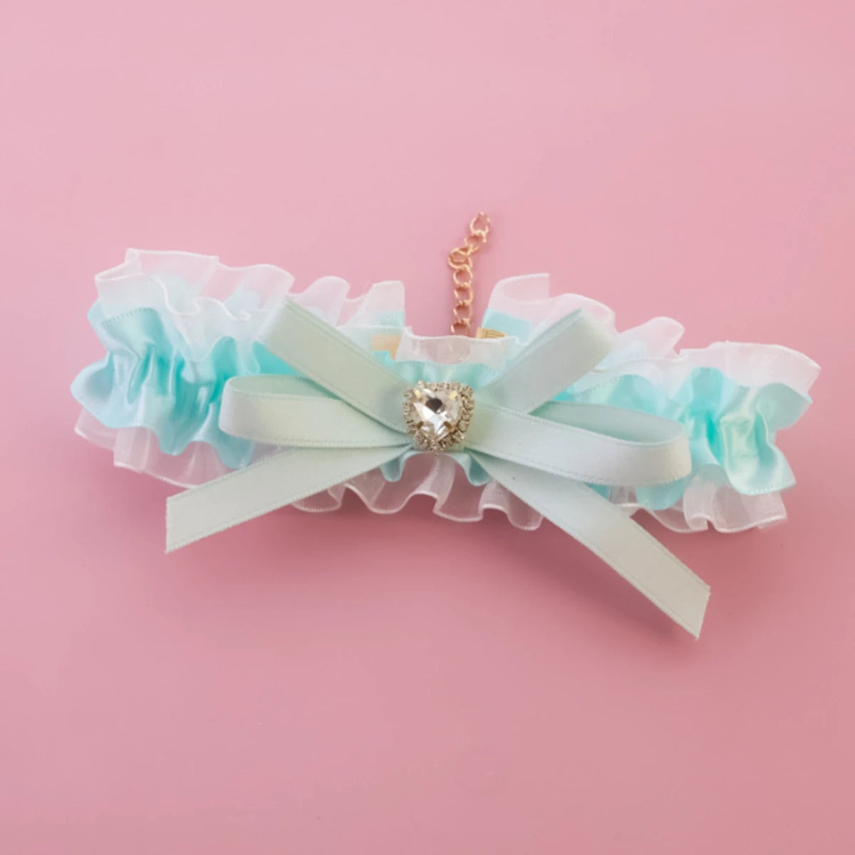 Jarretière décorative avec un nœud et un charme en forme de cœur sur fond rose

