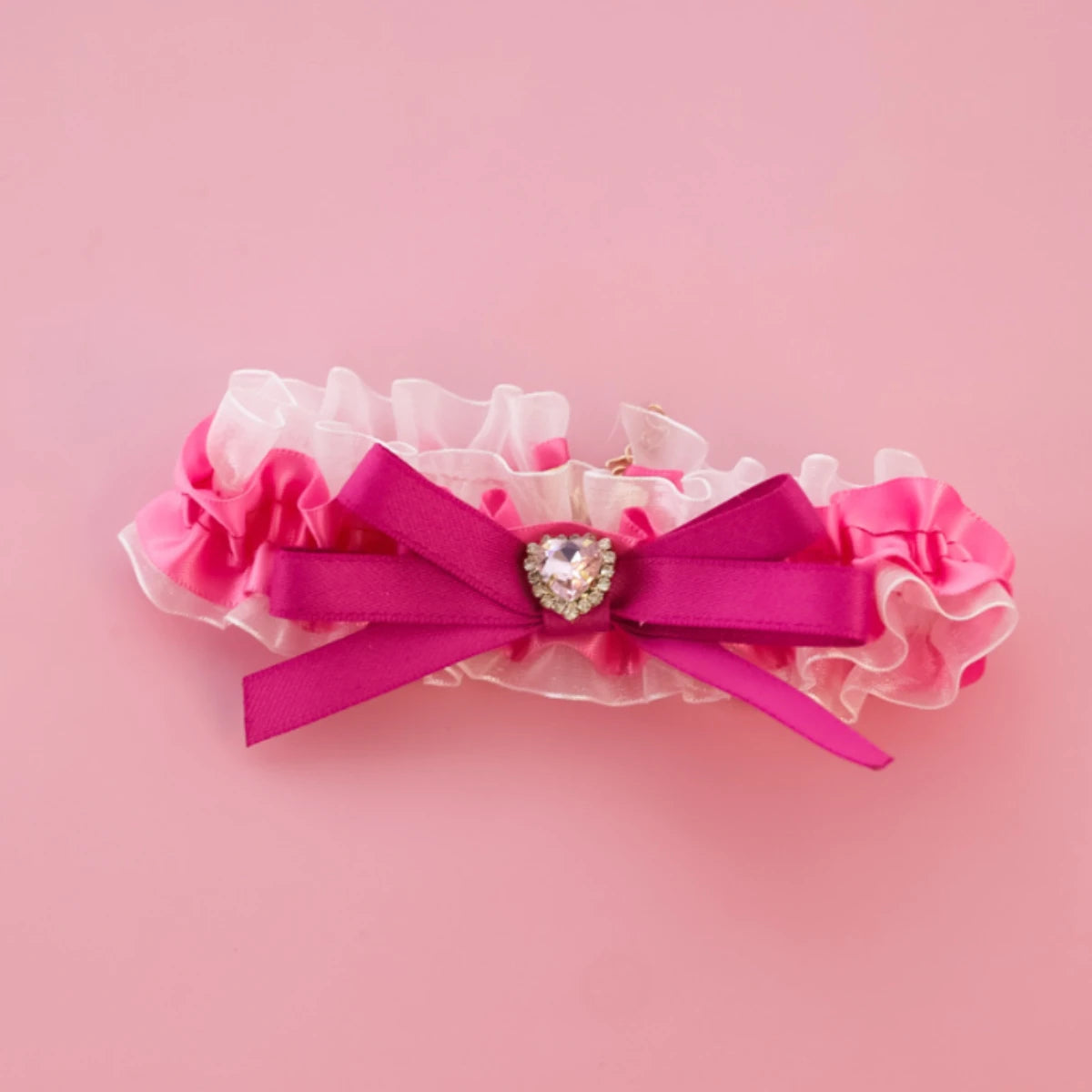 Nœud rose avec une pierre en forme de cœur sur fond rose

