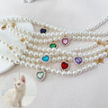 Collier de perles avec des pierres précieuses colorées en forme de cœur sur fond blanc

