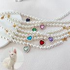 Collier de perles avec des pierres précieuses colorées en forme de cœur sur fond blanc


