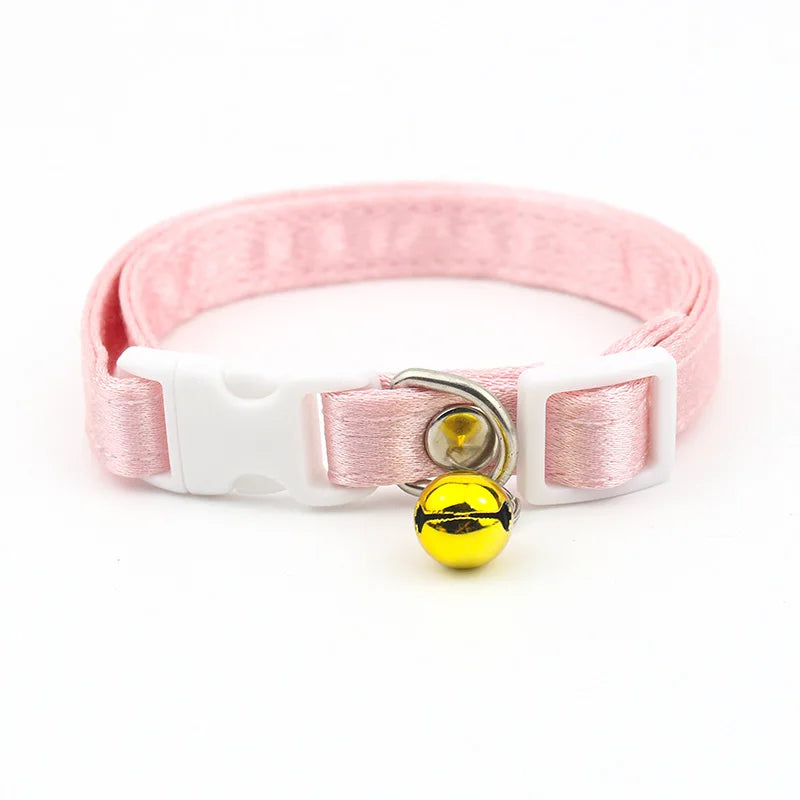 Collier rose pour chat avec une clochette jaune sur fond blanc

