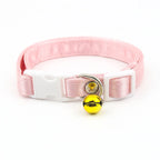 Collier rose pour chat avec une clochette jaune sur fond blanc

