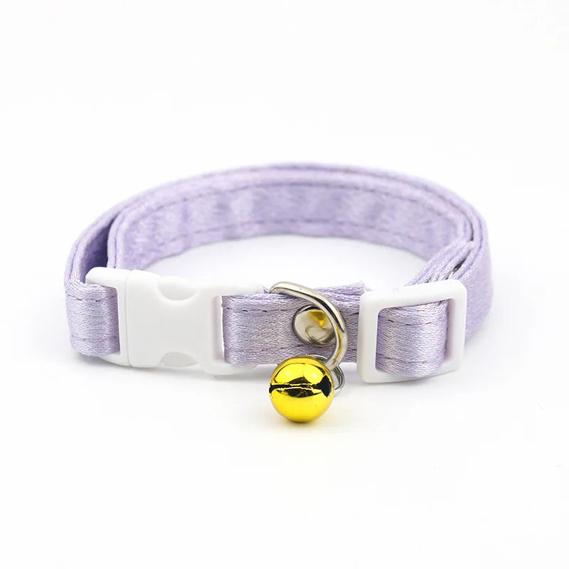 Collier violet avec une clochette dorée sur fond blanc


