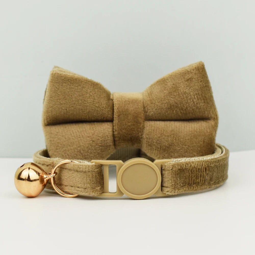 Collier marron avec nœud papillon et clochette dorée sur fond gris clair

