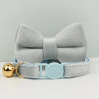Nœud papillon gris avec une boule dorée et une sangle bleu clair sur fond gris

