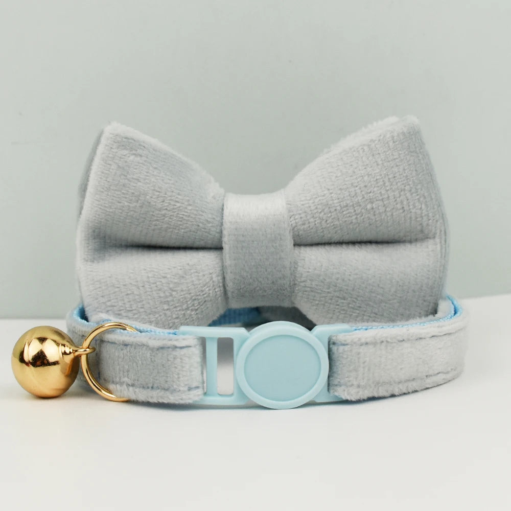 Nœud papillon gris avec une boule dorée et une sangle bleu clair sur fond gris

