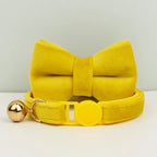 Collier jaune avec un grand nœud et une boule dorée sur fond clair
