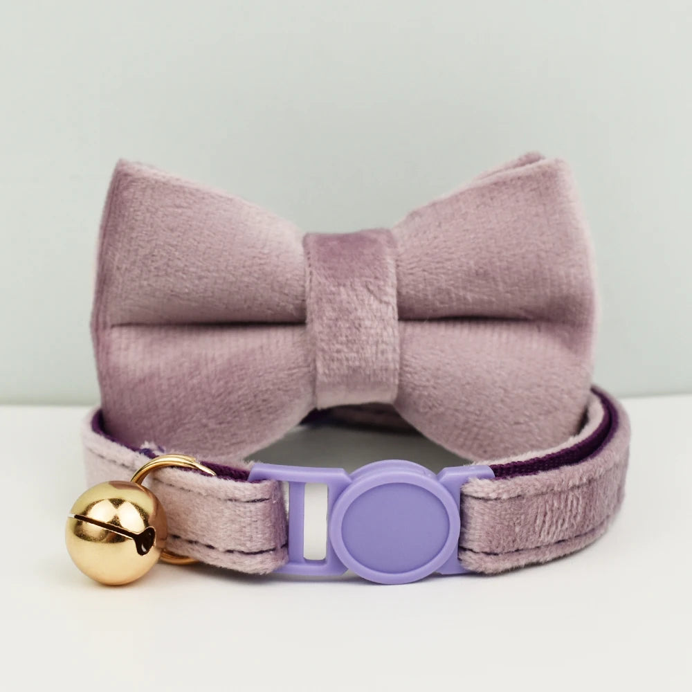 Col nœud papillon lavande avec une clochette dorée sur fond blanc
