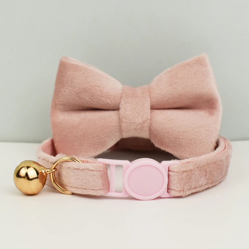 Col nœud papillon en velours rose avec fermoir doré sur fond clair

