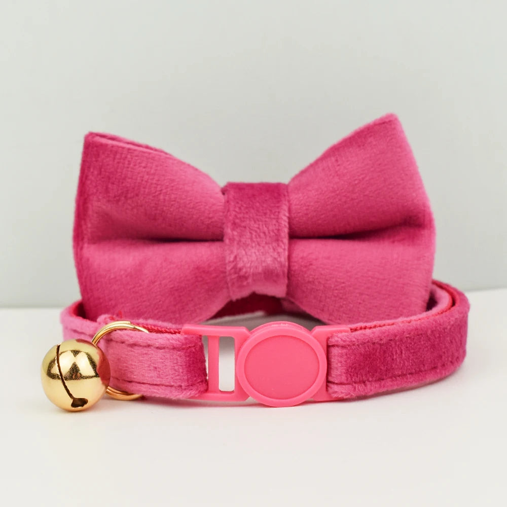 Col nœud papillon rose avec une clochette dorée sur fond blanc

