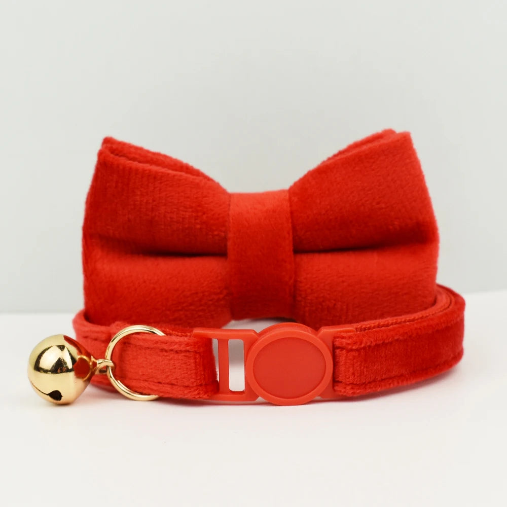 Col nœud papillon rouge avec une clochette dorée sur fond blanc

