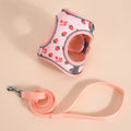 Harnais rose pour chat à motif fraise et laisse assortie sur fond beige

