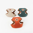 Trois harnais pour chiens beige, vert et orange sur fond blanc