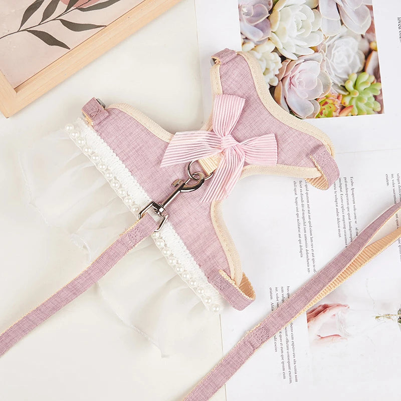 Harnais rose pour chien avec un nœud sur une surface blanche ornée de décorations florales

