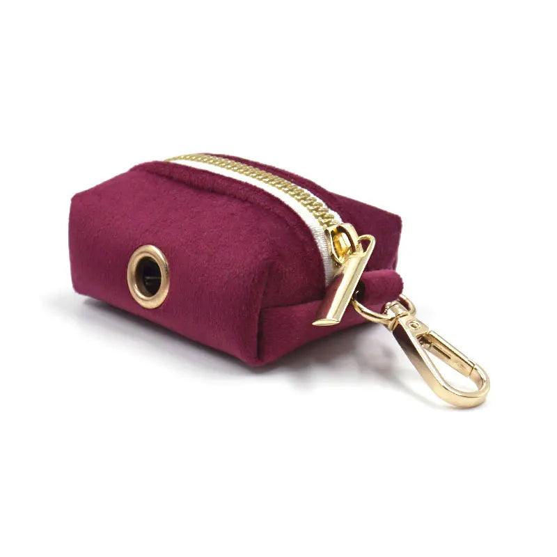 Pochette bordeaux avec fermeture éclair dorée et porte-clés sur fond blanc

