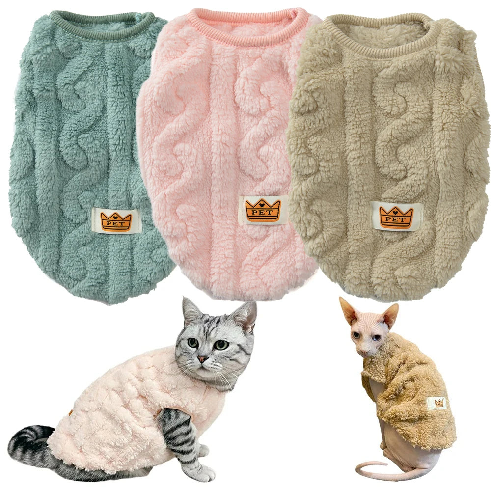 Trois pulls en maille torsadée pour animaux verts, rose et beige, portés par un chat et un petit chien.

